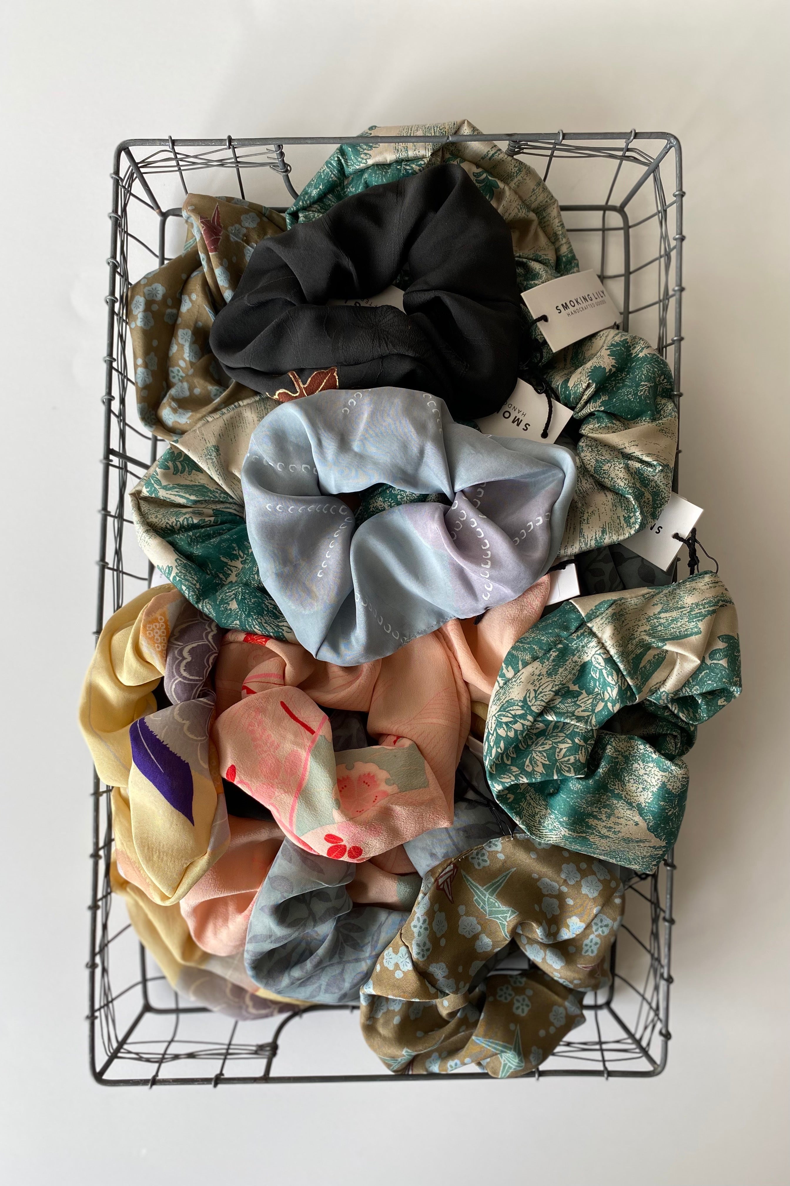 Wire basket full of puffy silk scrunchies of various colours and printed fabrics